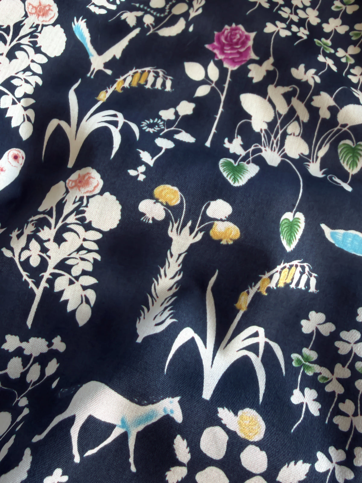 Yoshie is a novelty Liberty Japan print with cute woodland critters like stags, owls, and bunny rabbits. This print has metallic gold accents which are striking against the mottled navy background.